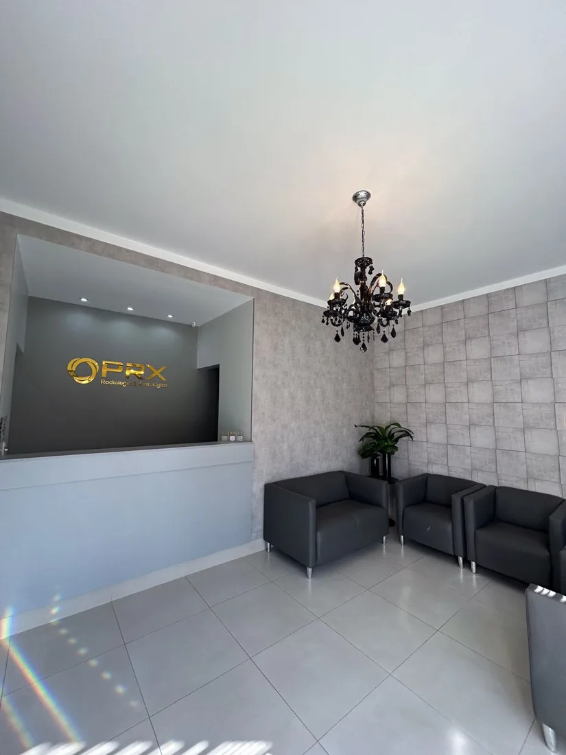 Recepção da PRX com sofás escuros e o logo dourado na parede